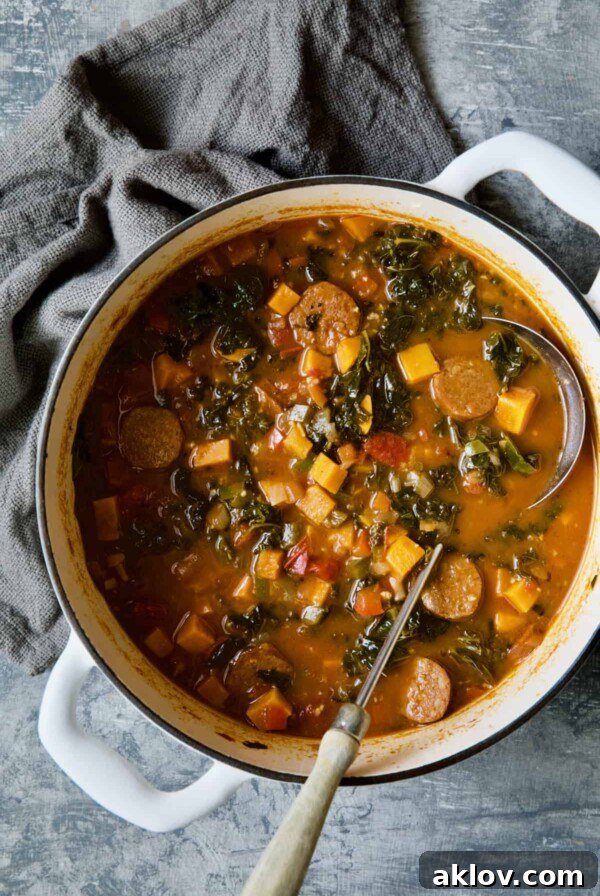 Chorizo Sweet Potato Stew with Kale in white Dutch oven with soup ladle.