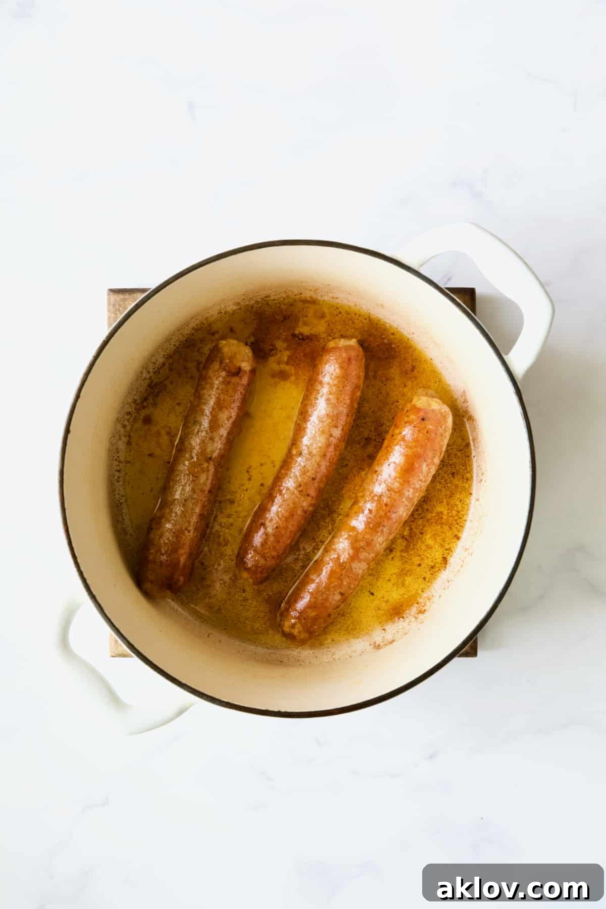 Three cooked chorizo links in white Dutch oven.