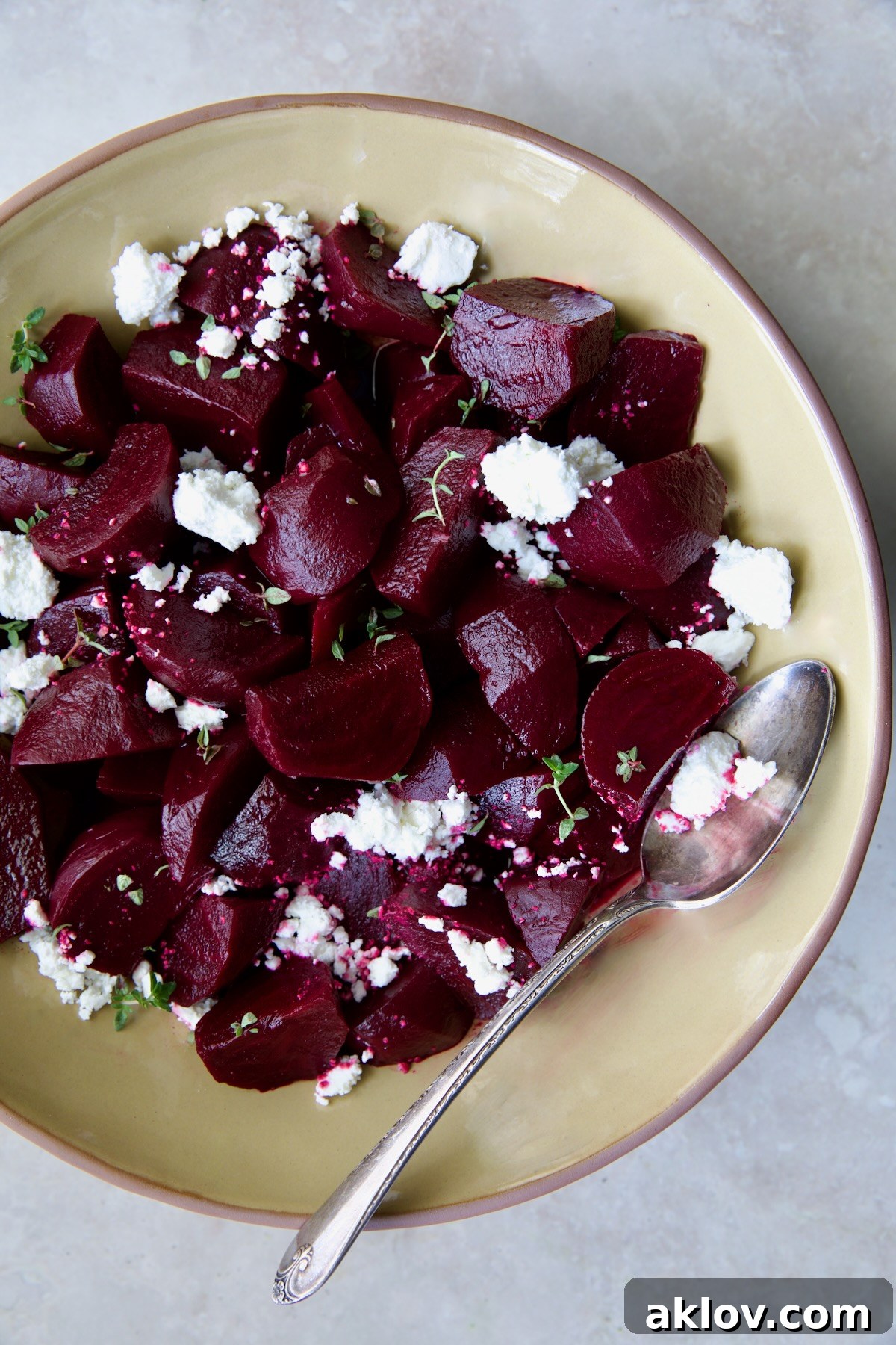 Beautifully roasted beets with red wine glaze, served in an earthenware bowl with a serving spoon and garnished with goat cheese.