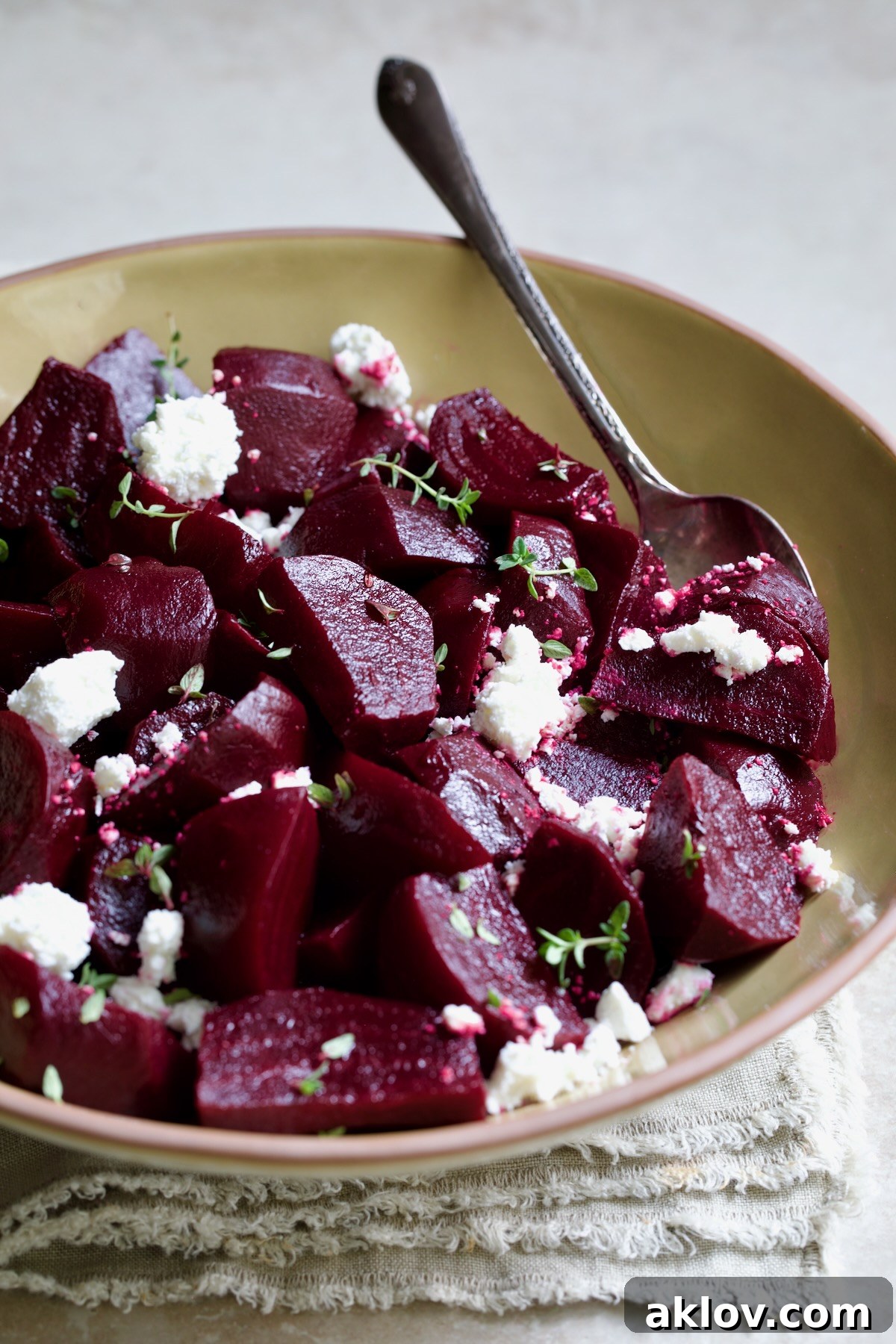 A close-up shot of roasted beets with red wine glaze, highlighting the texture of the goat cheese and fresh thyme garnish.