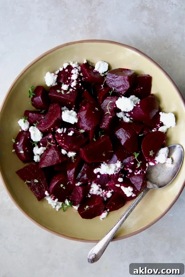 Roasted Beets with Red Wine Glaze in earthenware serving bowl with serving spoon sprinkled with goat cheese.