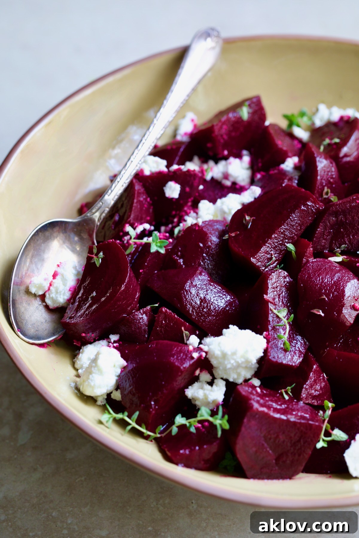 Serving bowl filled with roasted beets, garnished with crumbled goat cheese and fresh thyme.