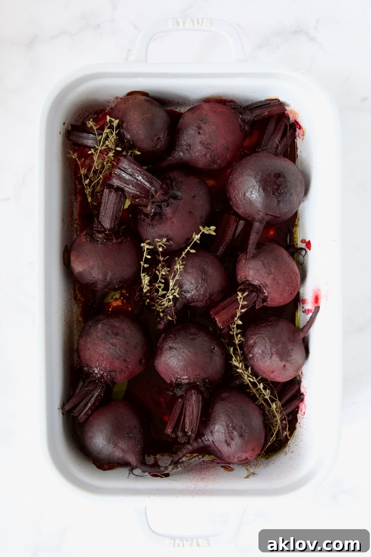 Perfectly roasted beets, soft and tender, resting in a white rectangular roasting dish after cooking.