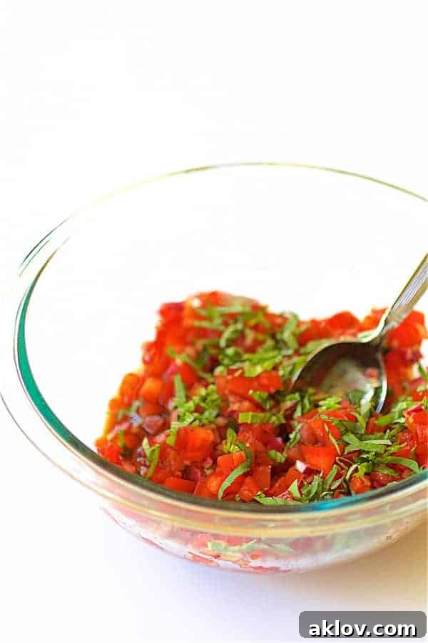 Pan-Seared Scallops with Vibrant Balsamic Tomato Salsa 15 Photo of tomato salsa and fresh basil being stirred in glass mixing bowl.