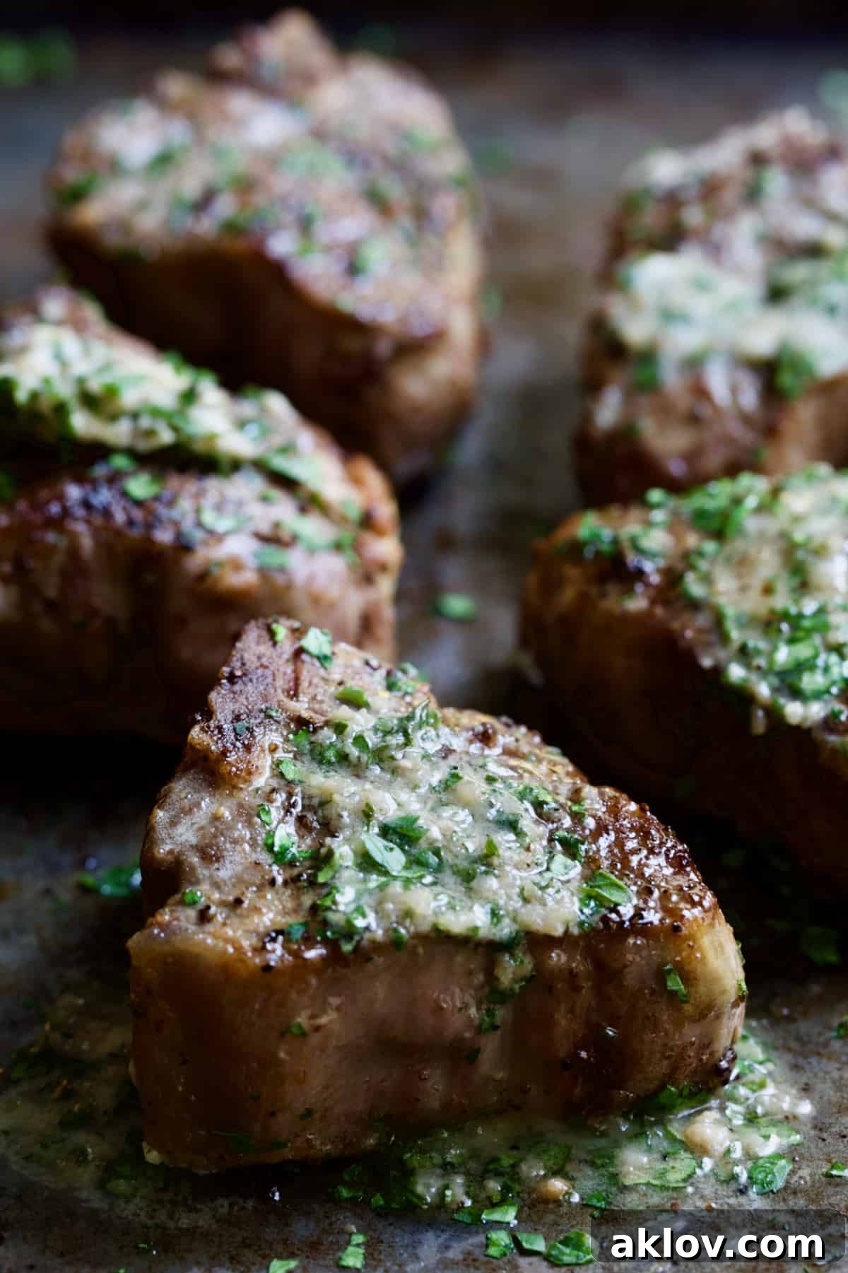 Close-up photo of a Seared Lamb Chop adorned with melting Anchovy Butter.