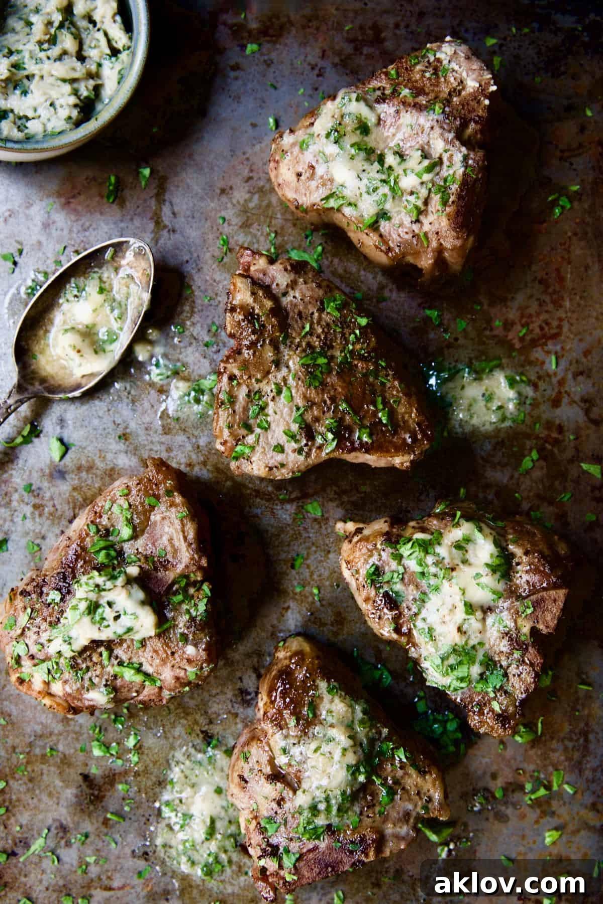 Seared Lamb Chops with Anchovy Butter on a rustic patinated baking sheet.