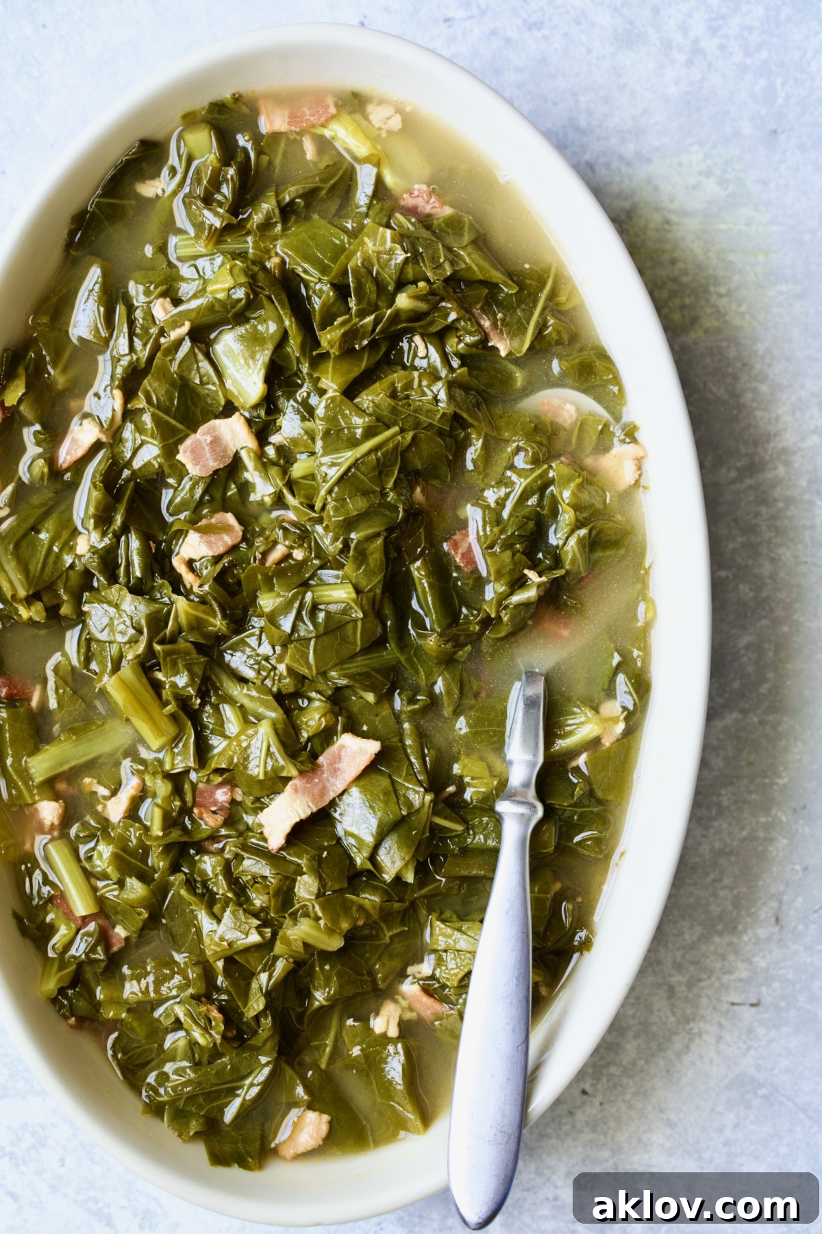 Braised Southern Greens in oval serving bowl with serving spoon.