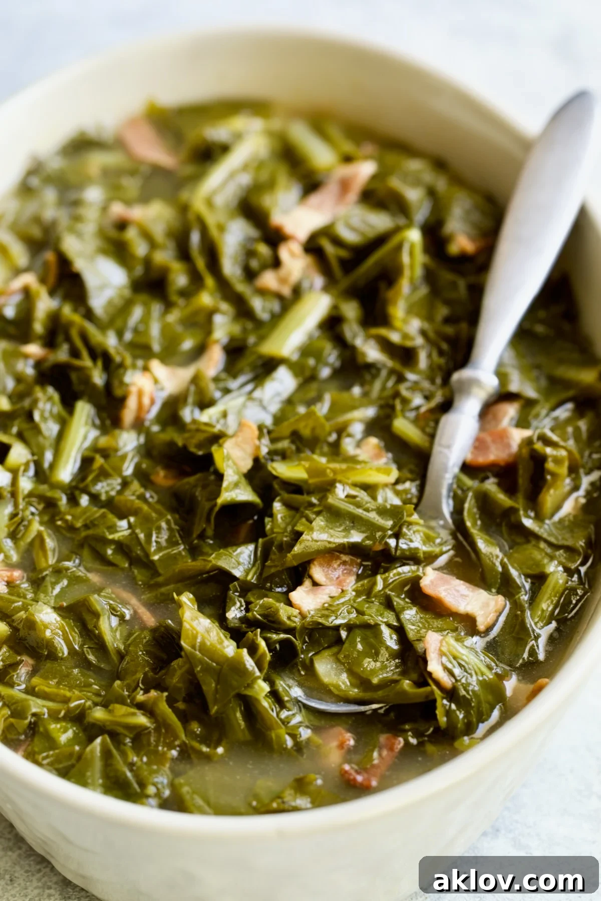Braised Southern Greens in oval serving bowl with serving spoon.