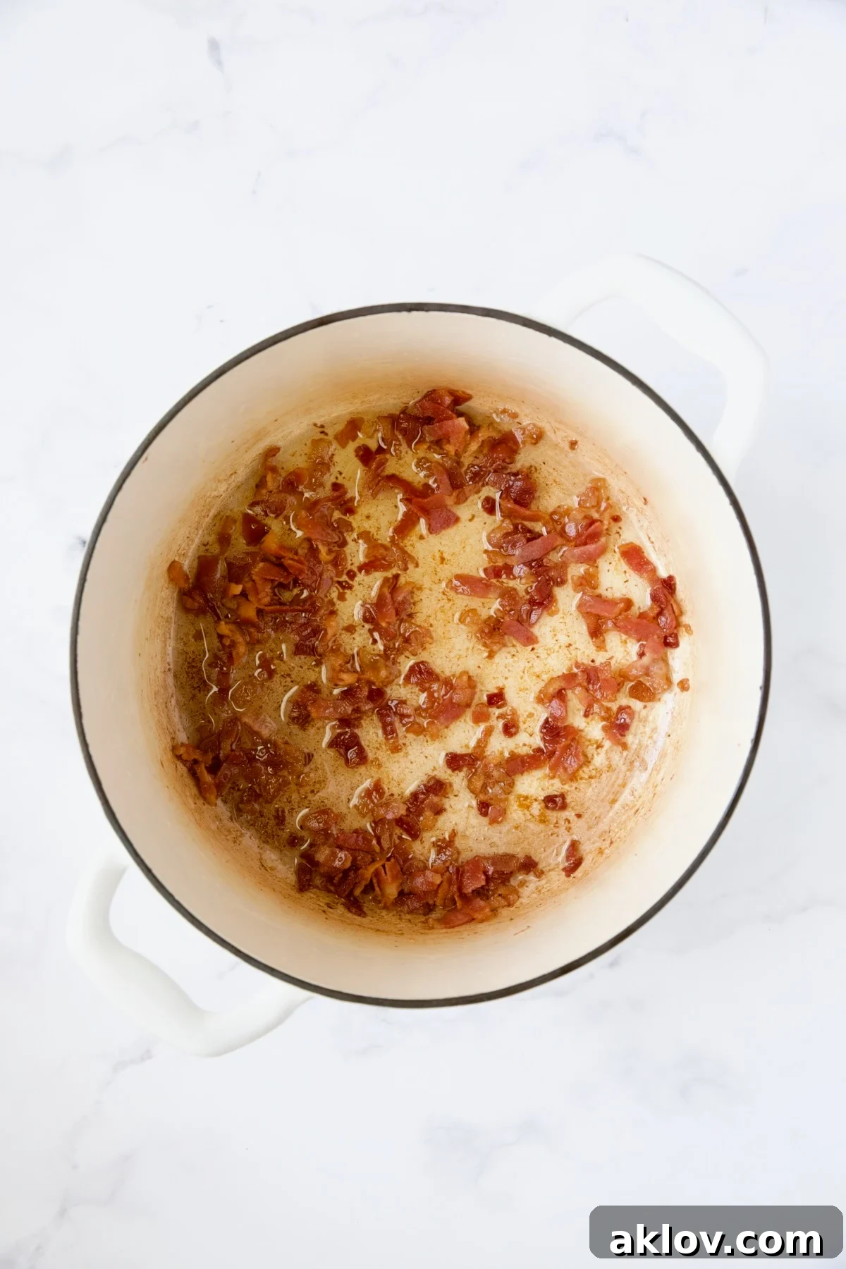Cooked bacon in white Dutch oven.