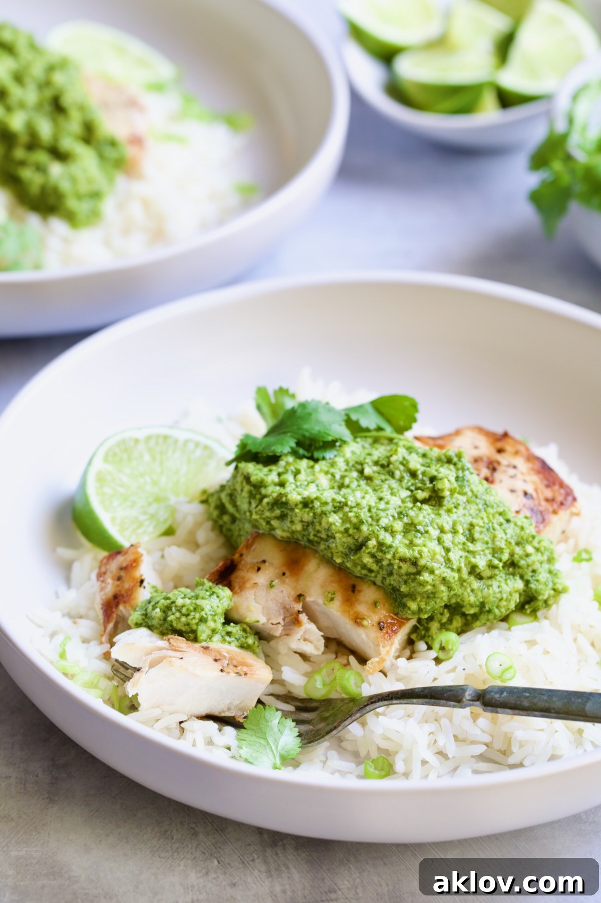 Close-up of a serving of Mahi Mahi with Cilantro-Ginger Pesto in a white bowl, with a fork taking a piece, showcasing the tender texture and vibrant pesto.