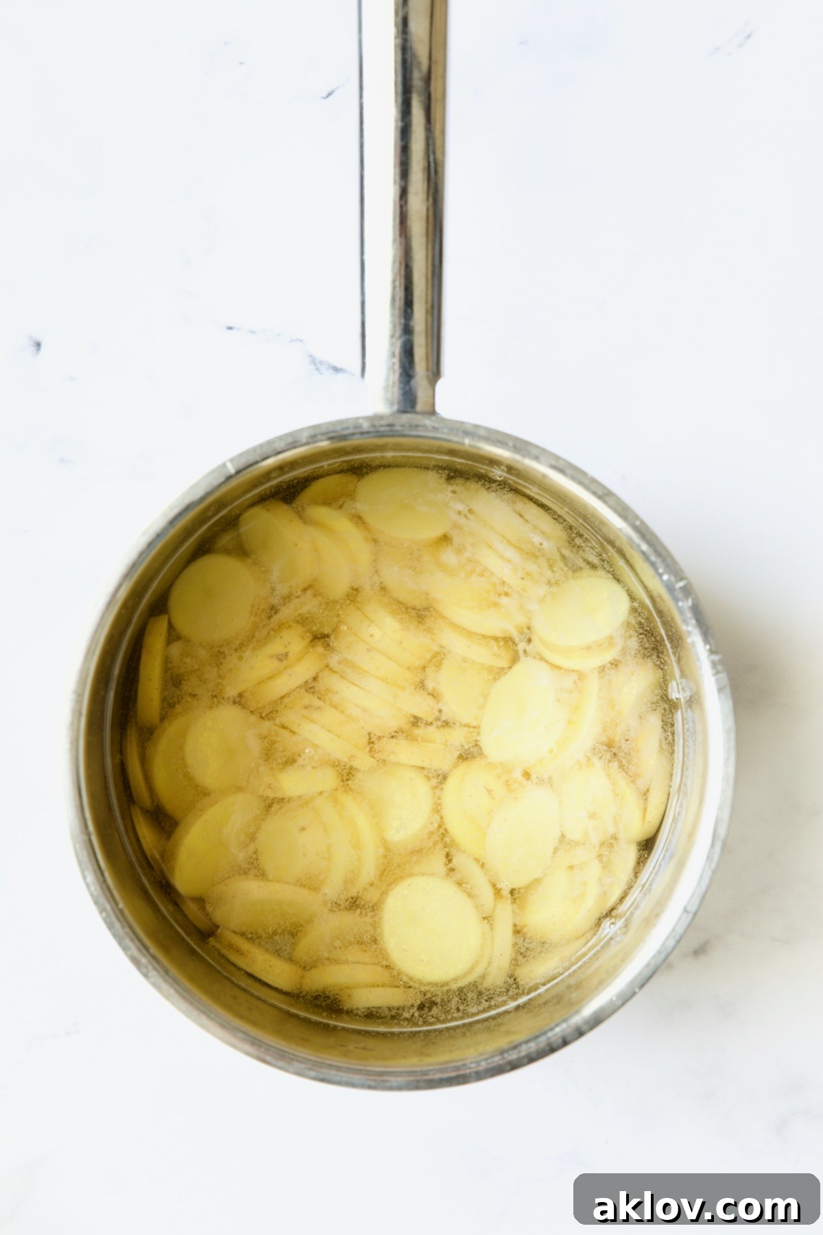 Cooked potato slices in saucepan.
