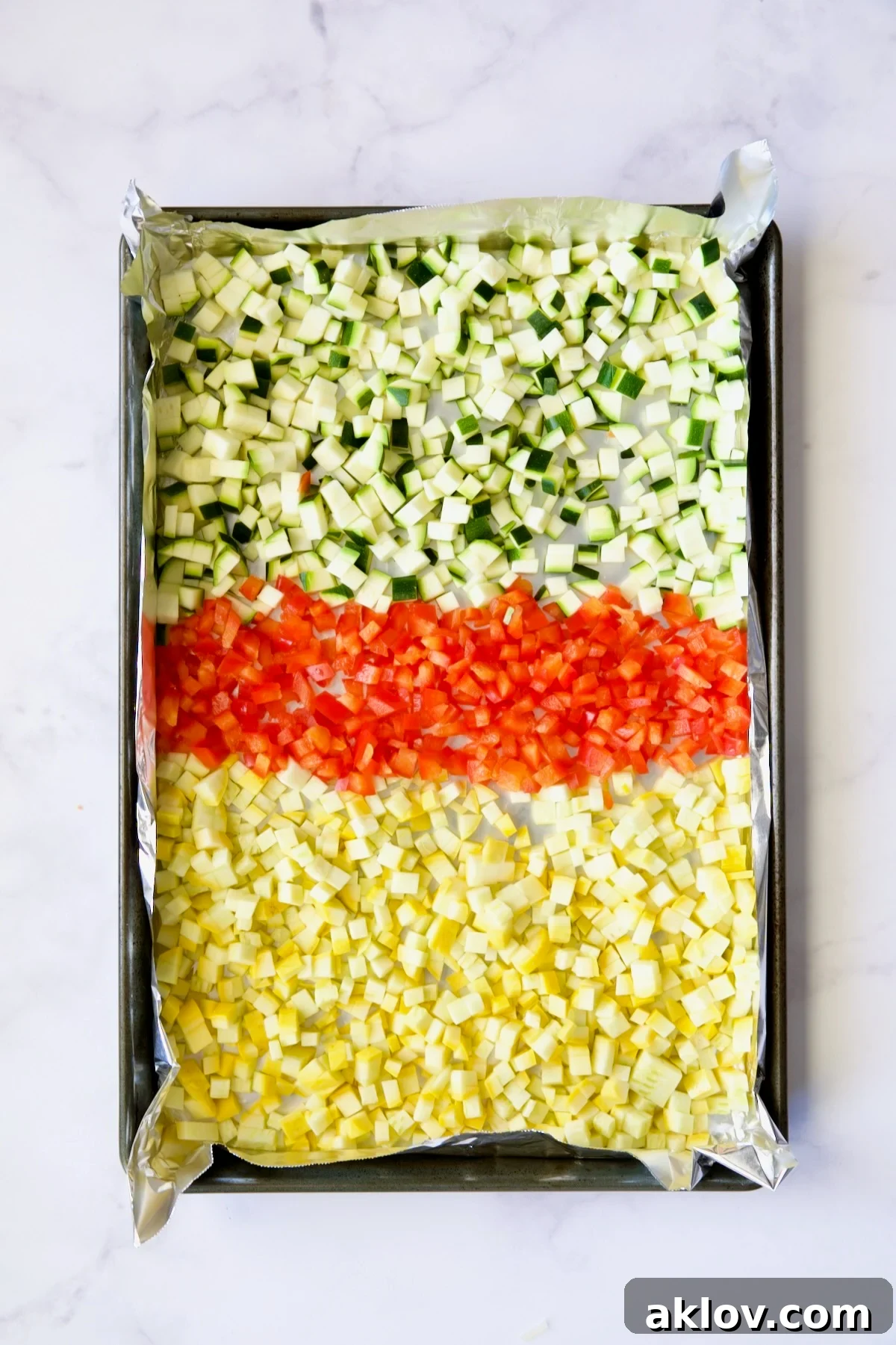 Garlic Parmesan Roasted Riced Veggies 7 Diced zucchini, yellow squash and red bell pepper on aluminum foil-lined baking sheet before being roasted.