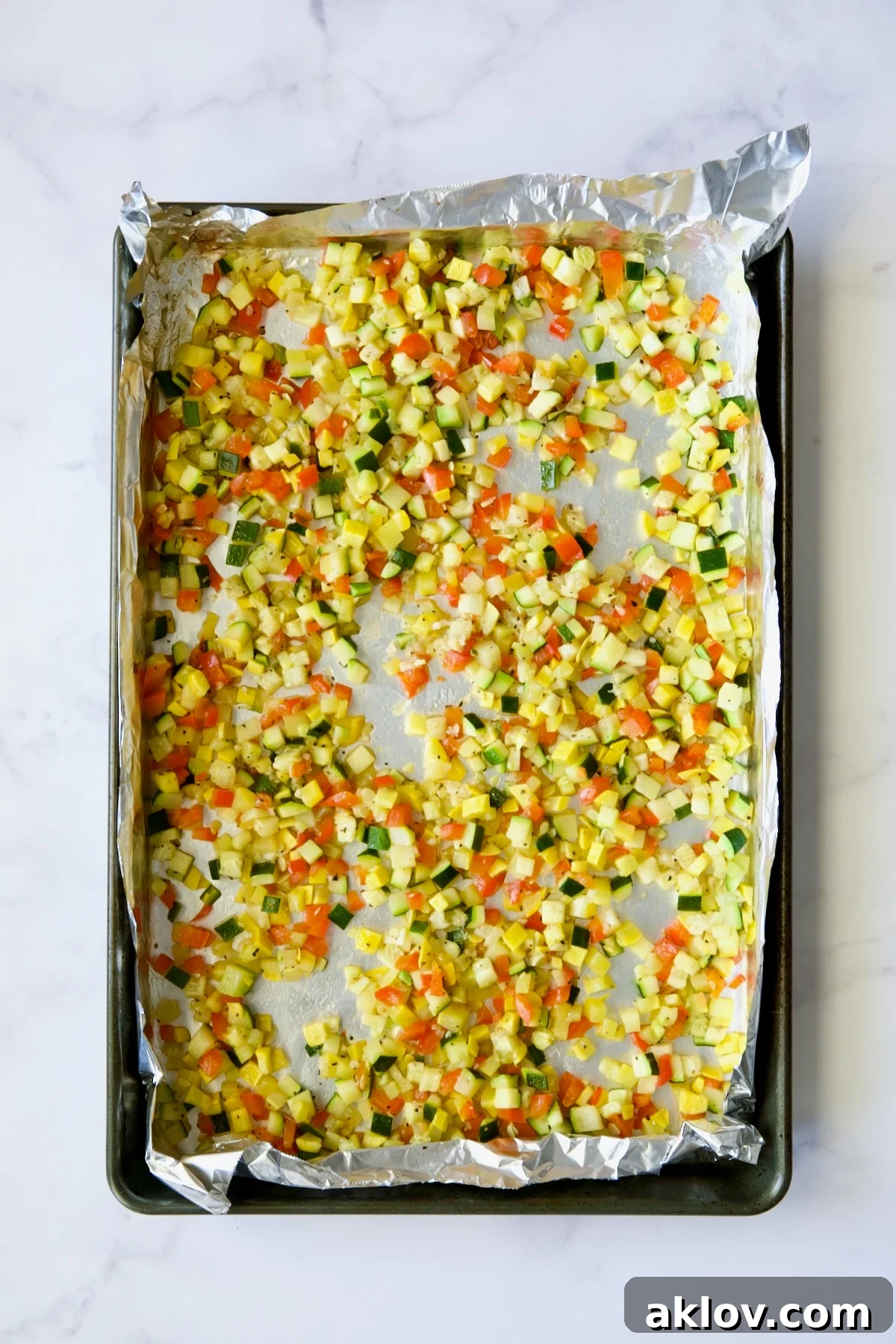 Garlic Parmesan Roasted Riced Veggies 9 Diced roasted zucchini, yellow squash, and red bell pepper on aluminum foil-lined baking sheet, after the second roast.
