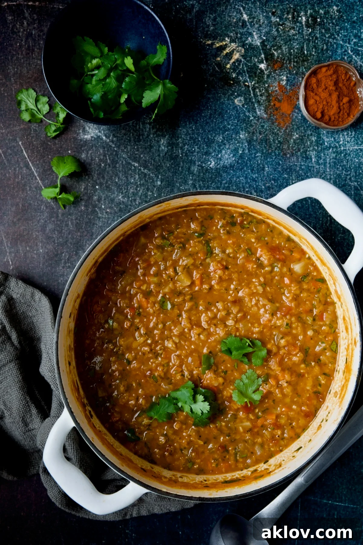 Ethiopian Red Lentil and Vegetable Stew in a white Dutch oven, presented alongside a small bowl of fresh cilantro and a dish of authentic berbere spice blend.