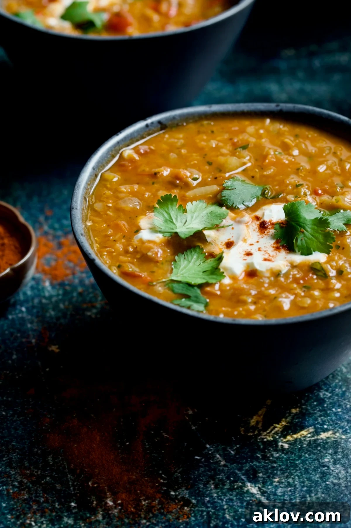 A single, inviting bowl of vibrant Ethiopian Red Lentil and Vegetable Stew, beautifully presented against a rustic blue distressed background, ready to be enjoyed.