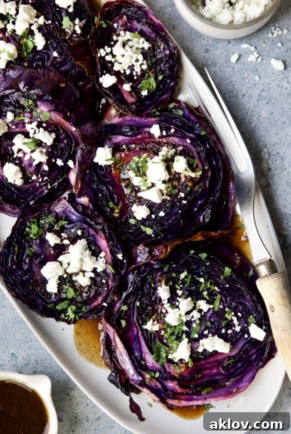 Roasted Red Cabbage Steaks with Balsamic Vinaigrette and Goat Cheese on white platter with serving fork.
