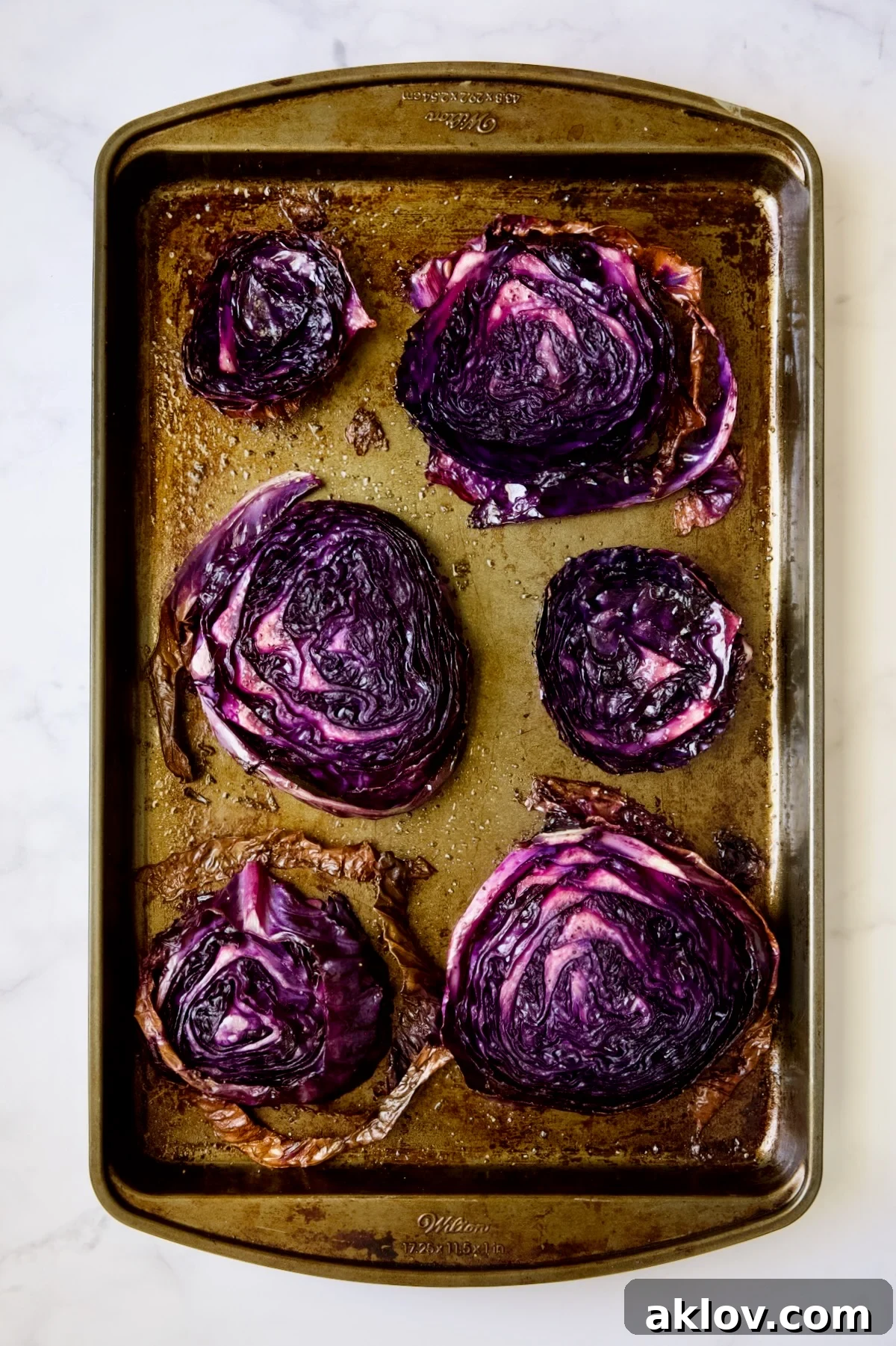Six roasted red cabbage steaks on baking sheet.