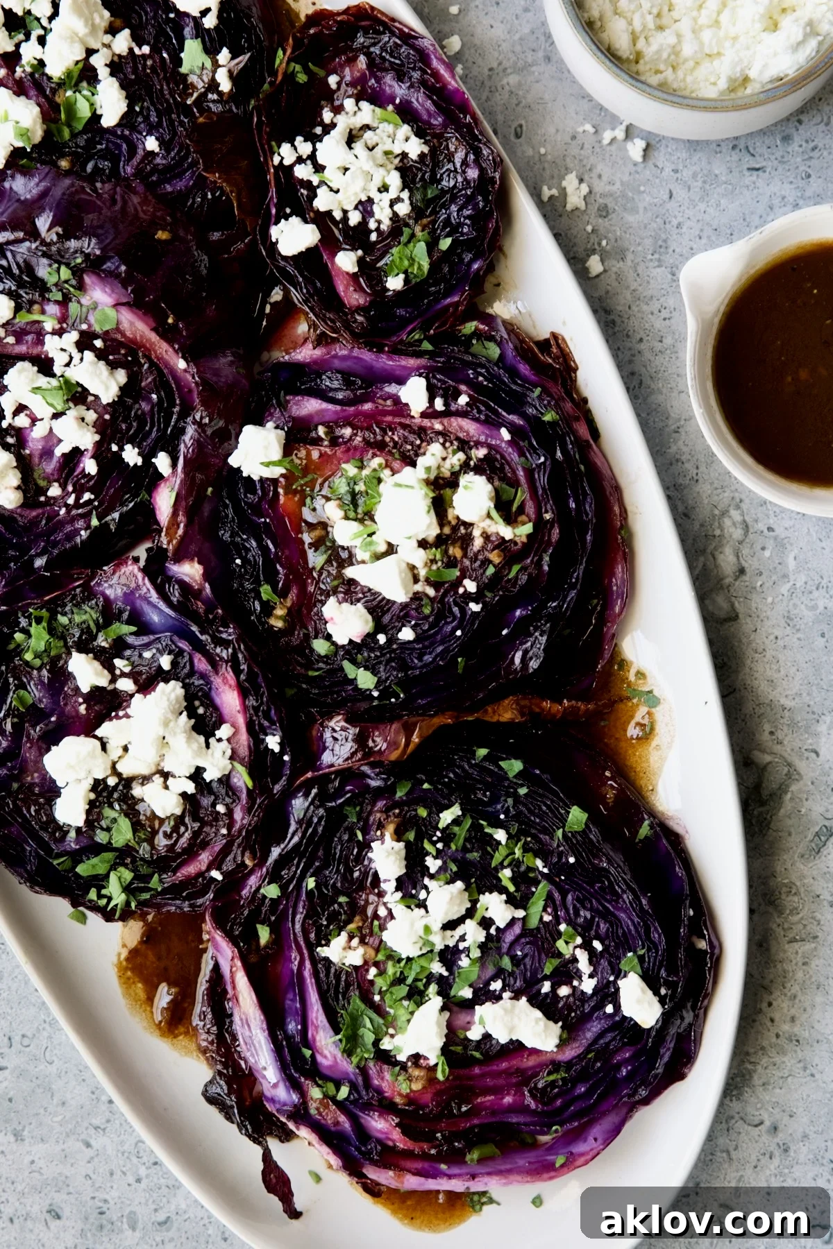 Roasted Red Cabbage Steaks with Balsamic Vinaigrette and Goat Cheese on white platter.