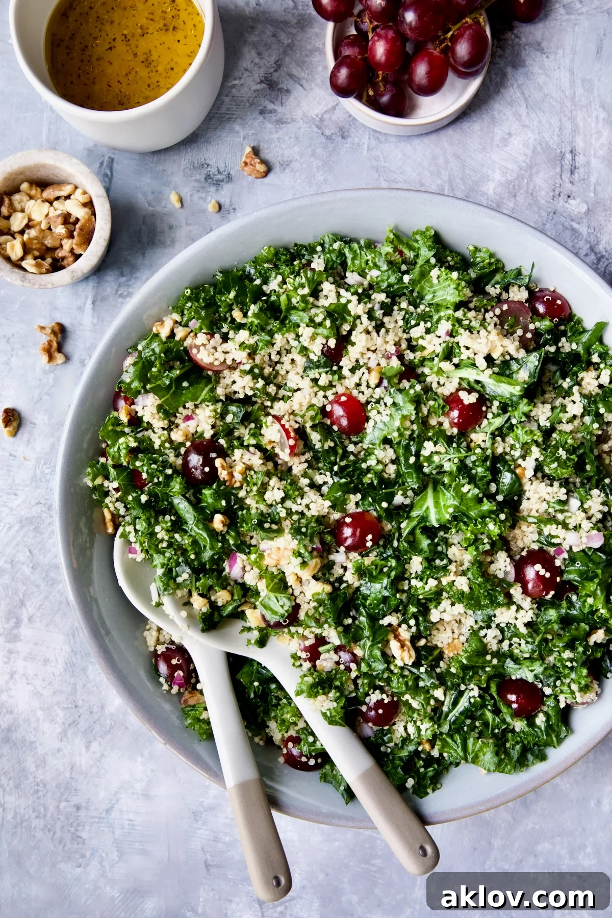 Vibrant Kale Quinoa Salad with Lemon Honey Dressing elegantly presented in a gray serving bowl with serving utensils, ready to be enjoyed.