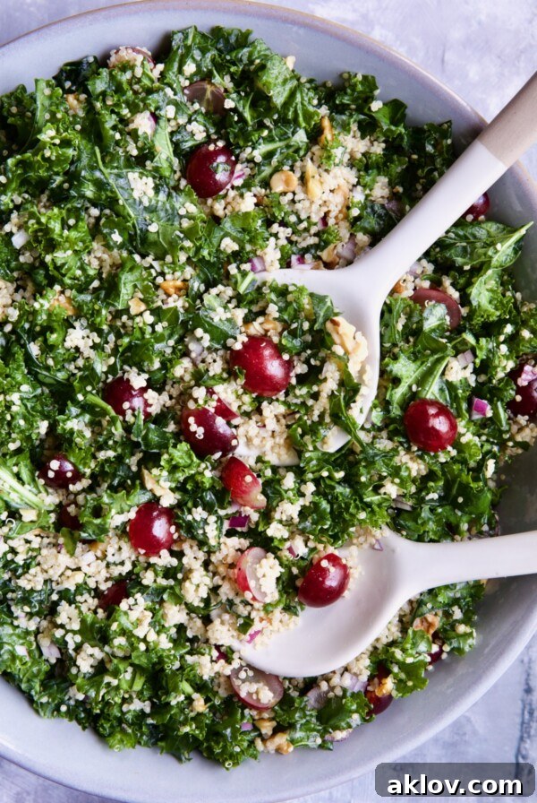 Kale Quinoa Salad with Lemon Honey Dressing in gray serving bowl with serving utensils.