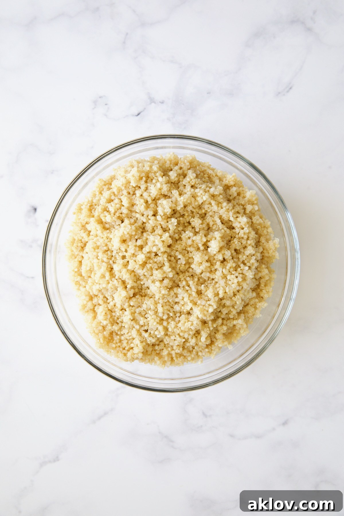 Fluffy, perfectly cooked quinoa resting in a clear glass bowl, cooled and ready for the salad.