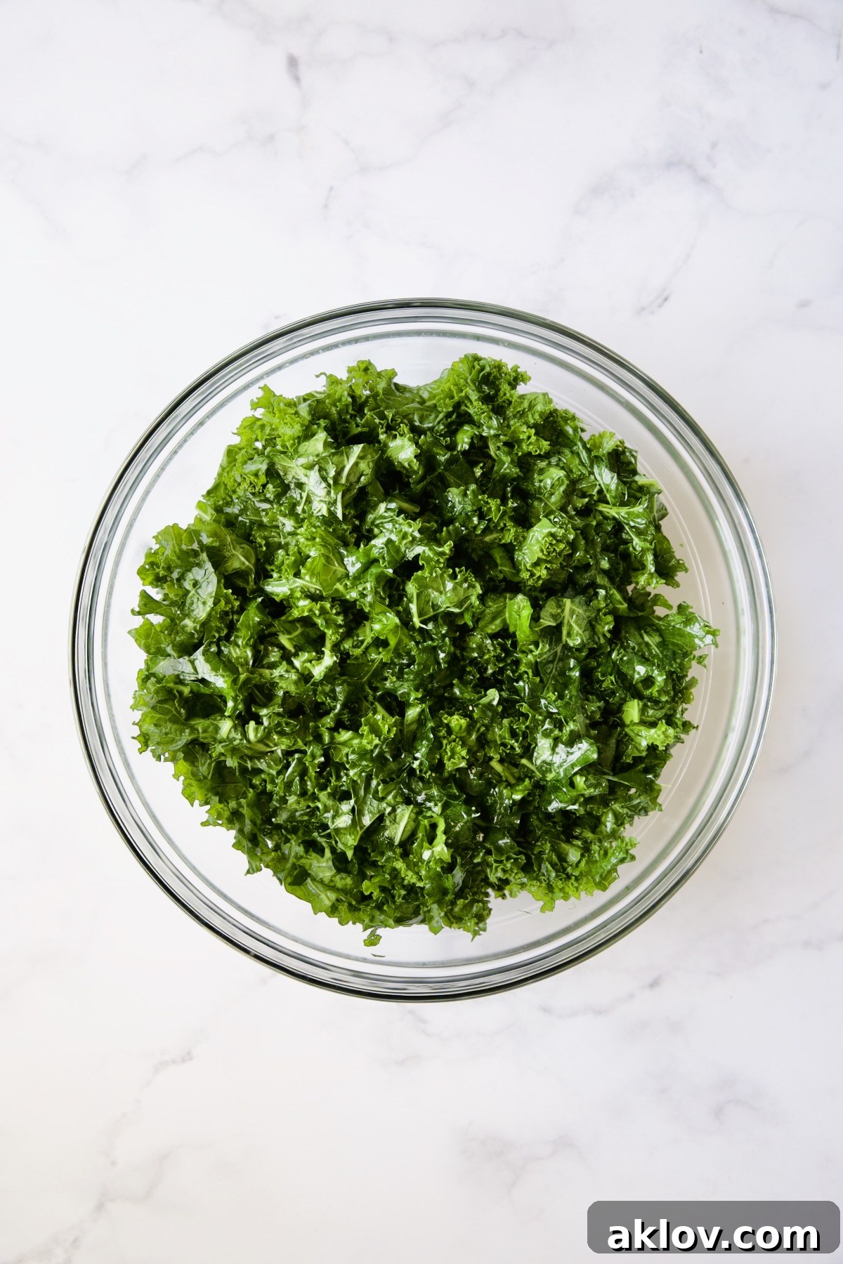 Gently massaged and wilted kale leaves in a glass bowl, showcasing their softened texture.