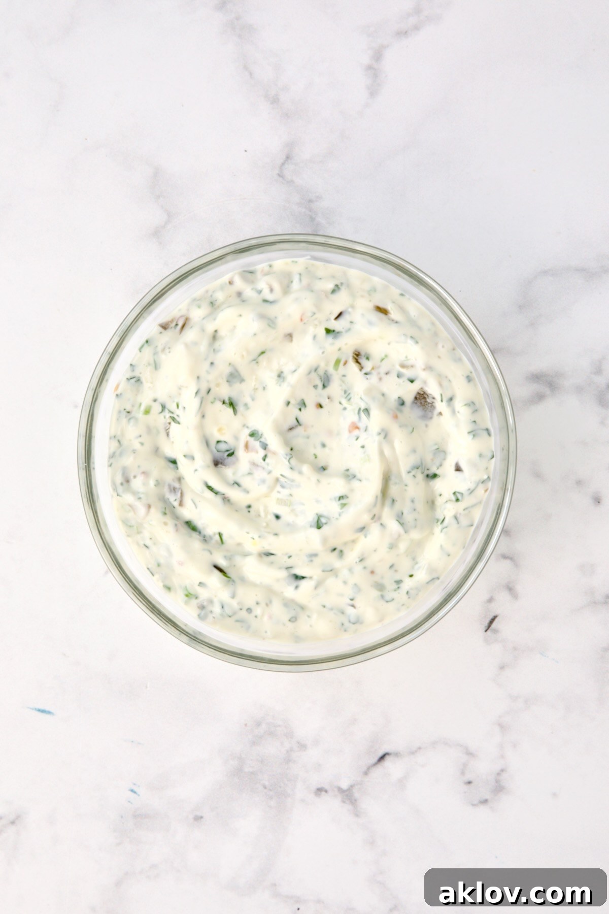 Crispy Chickpea-Crusted Fish with Zesty Jalapeno Tartar 5 Fresh ingredients for the spicy jalapeno tartar sauce are combined in a glass bowl.