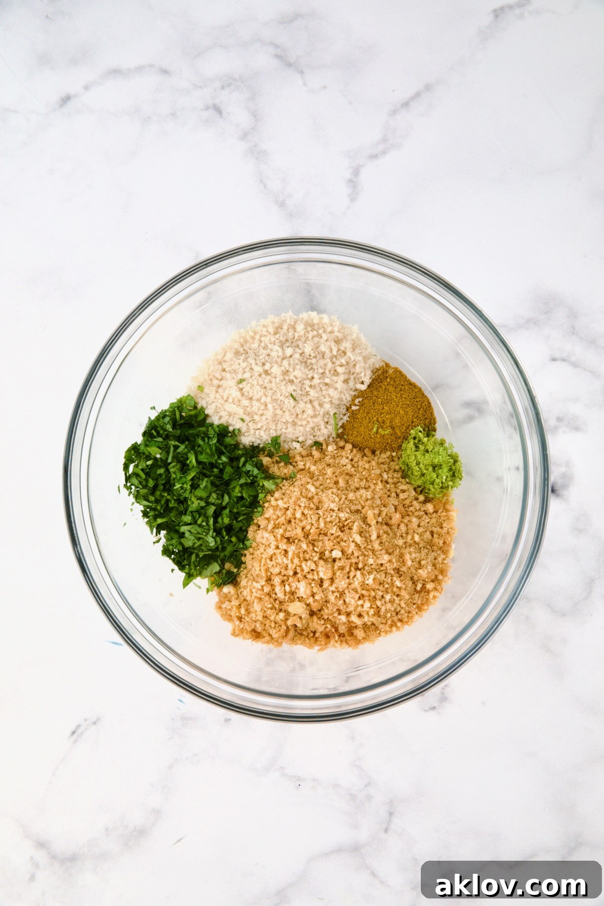 Crispy Chickpea-Crusted Fish with Zesty Jalapeno Tartar 7 Separate ingredients for the chickpea topping, including curry powder, panko, lime zest, and cilantro, in a glass bowl.