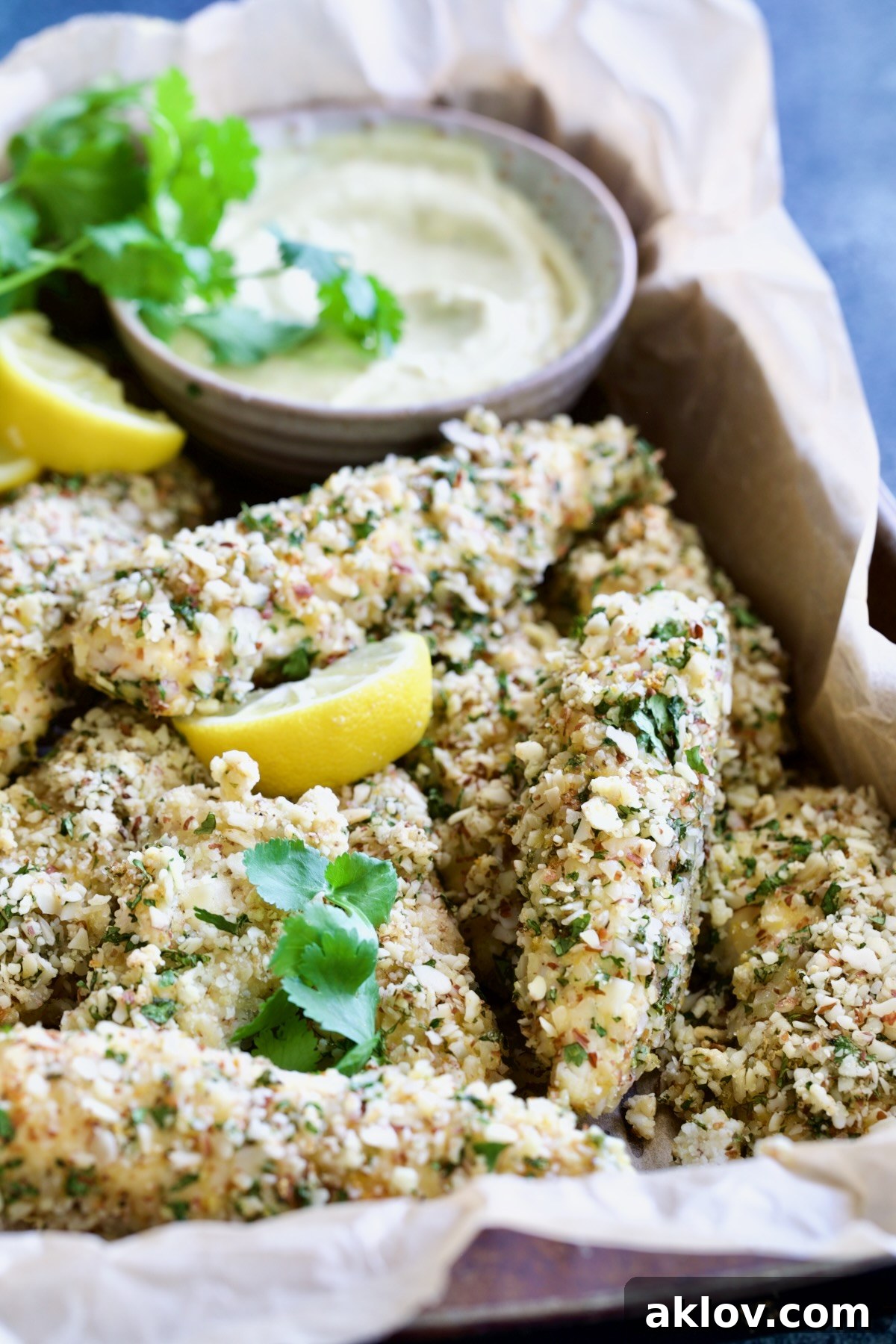Almond-Crusted Chicken Tenders with Lemon Curry Mayonnaise in parchment paper-lined pan.
