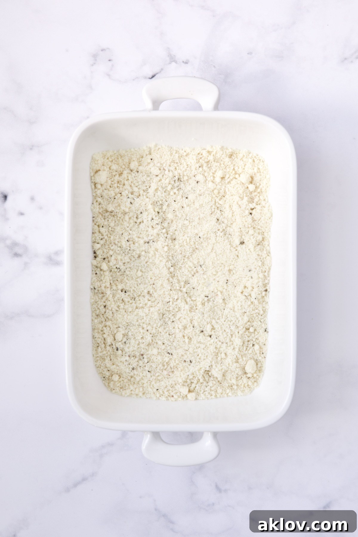 Seasoned almond flour in white rectangular baking pan.