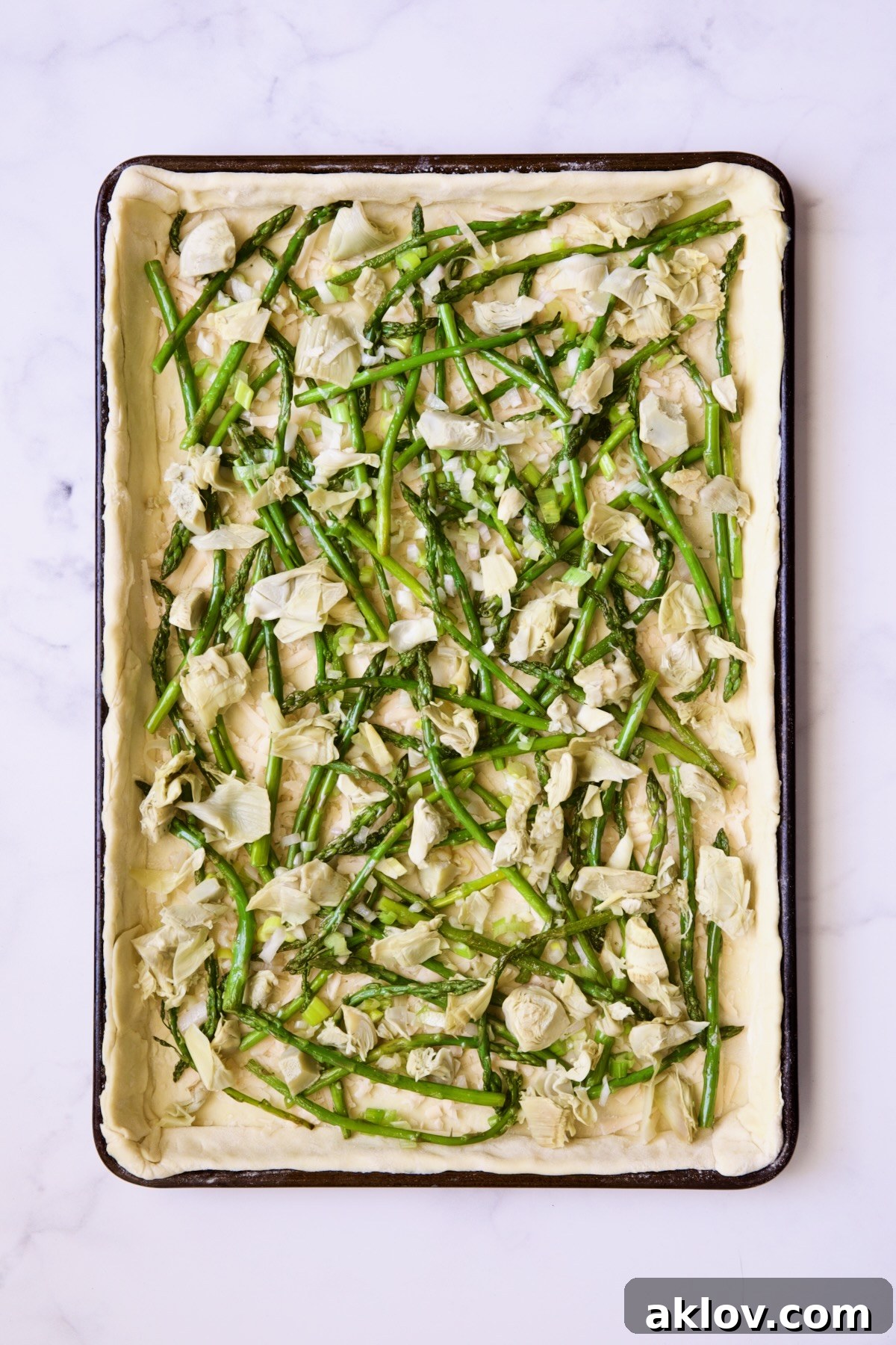 Tart before being baked with asparagus, artichokes and scallions.