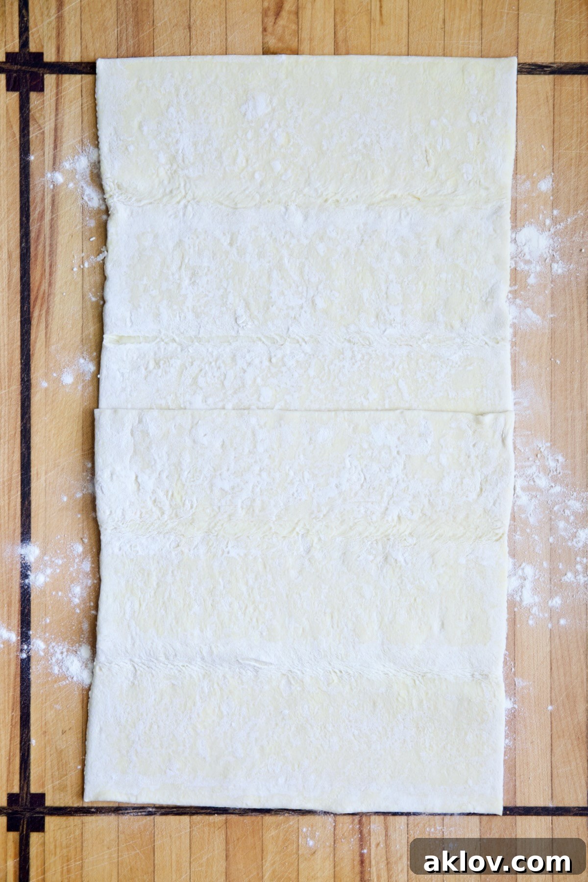 Puff pastry crust on wood cutting board before being rolled out.