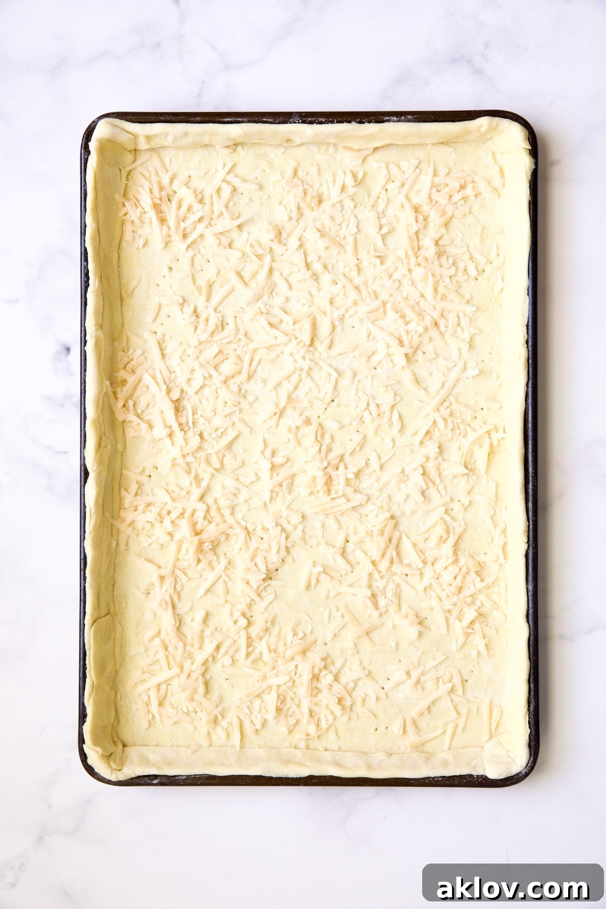 Puff pastry crust with layer of cheese sprinkled over it.