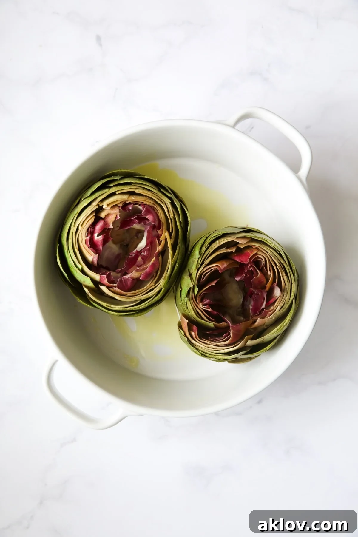 Savory Italian Stuffed Artichokes 14 Two artichokes in white baking dish before being stuffed.