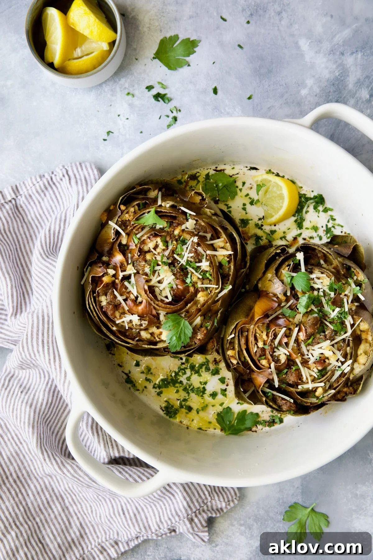 Savory Italian Stuffed Artichokes 17 Two Italian-Stuffed Artichokes in white baking dish garnished with fresh parsley.