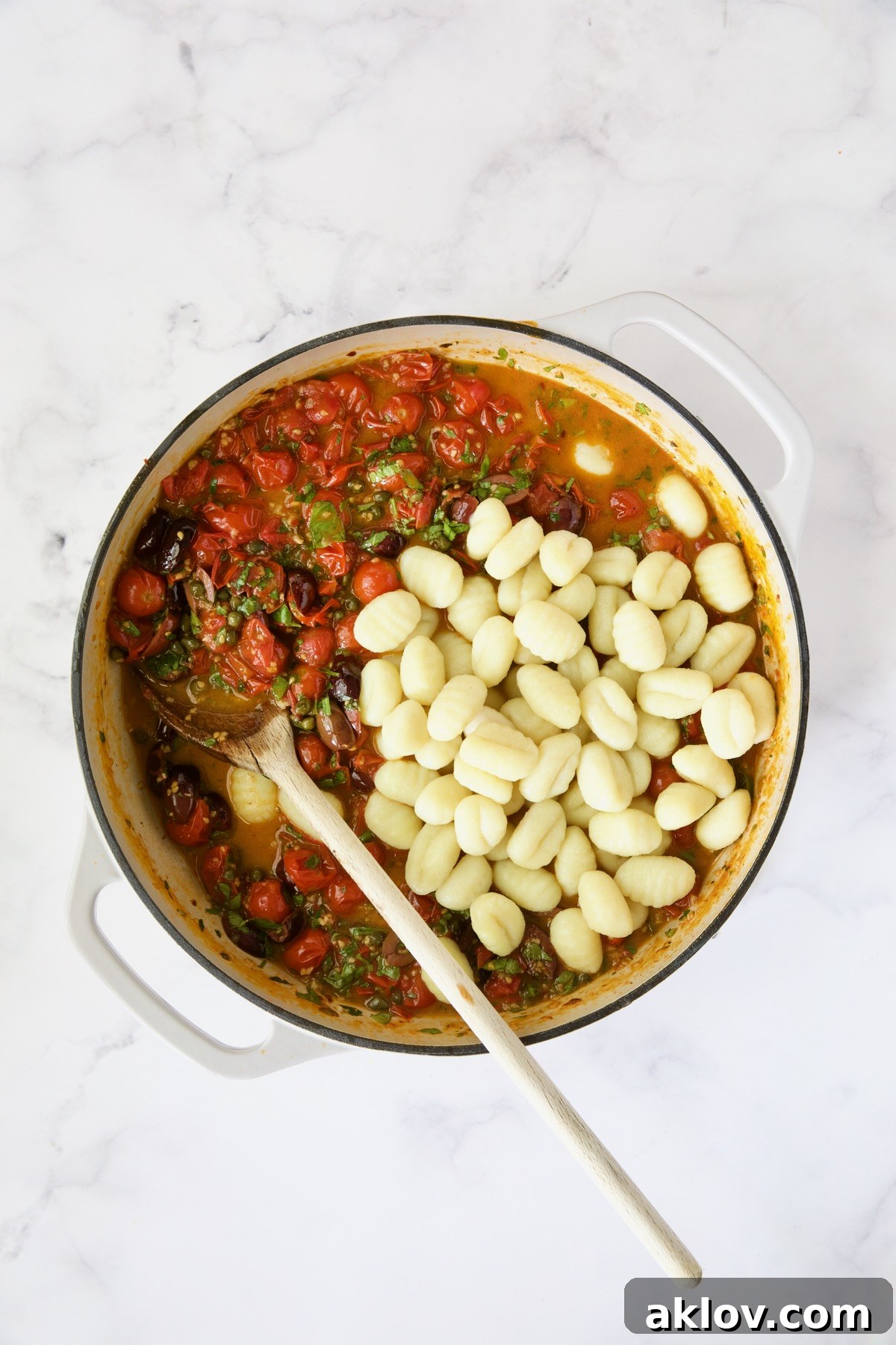 Puttanesca sauce in white enamel cast iron skillet with gnocchi added but not stirred in.