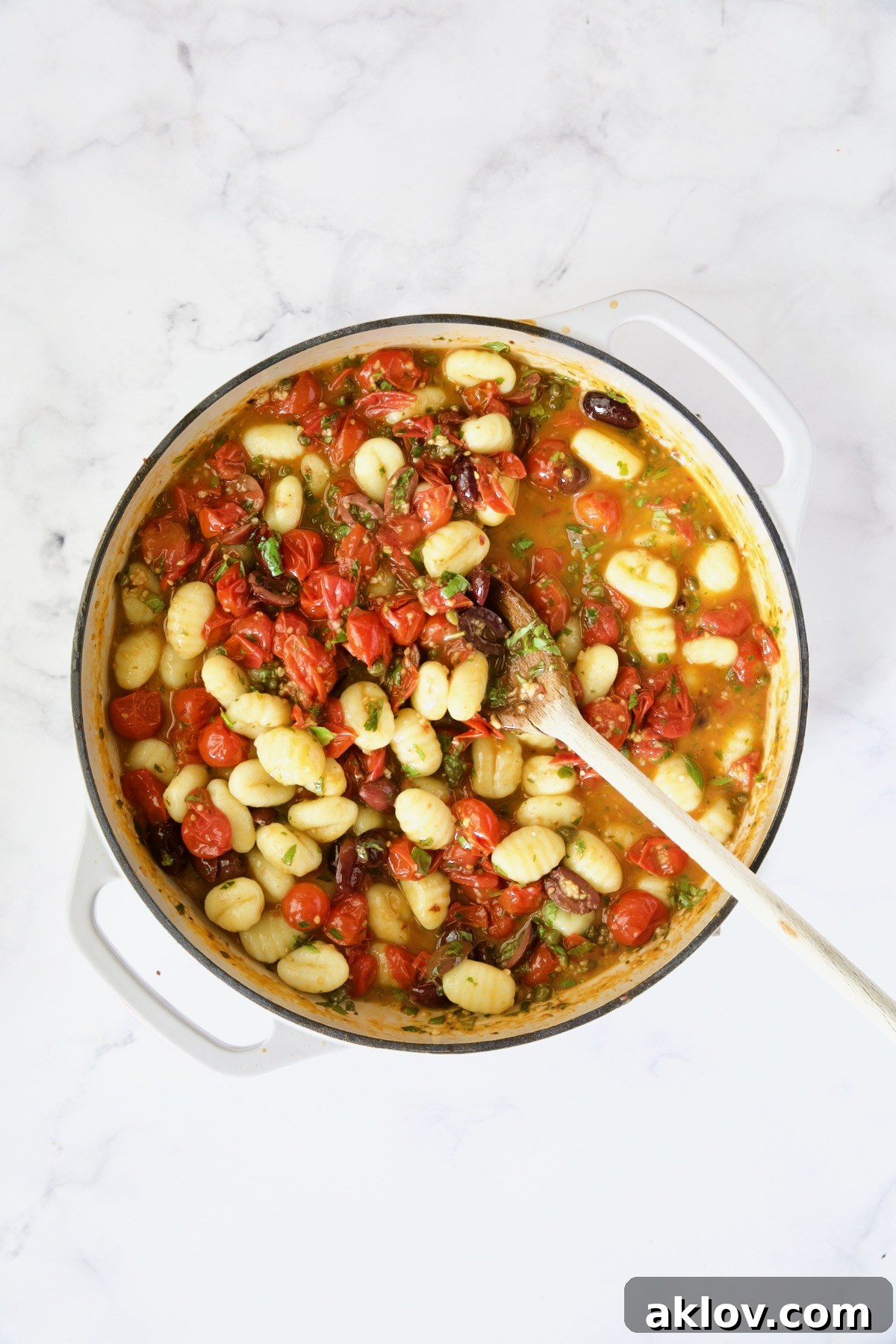 Gnocchi with the puttanesca sauce in white enamel cast iron skillet.