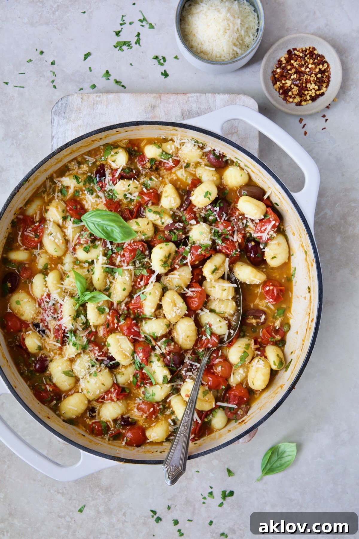 Gnocchi with Cherry Tomato Puttanesca Sauce in white enamel cast iron skillet on white board.