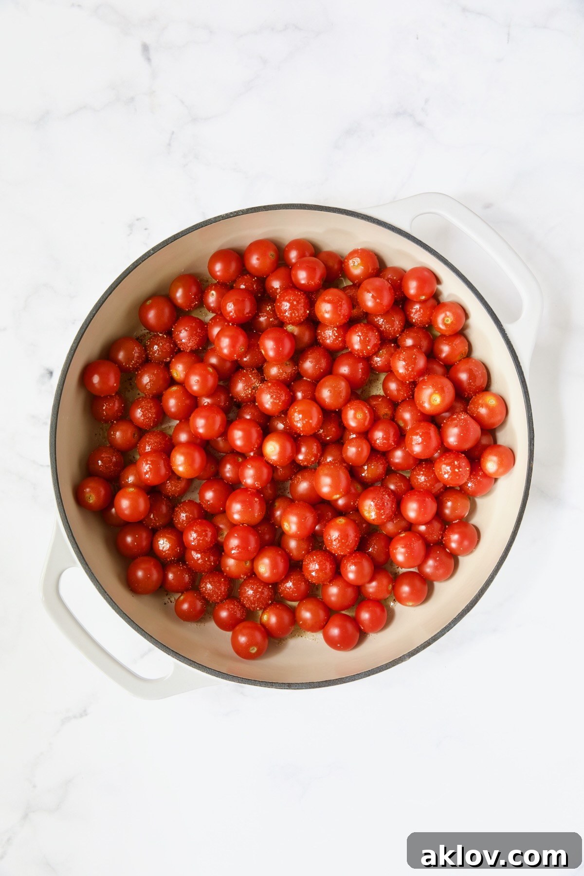 Uncooked cherry tomatoes in white enamel cast iron skillet.