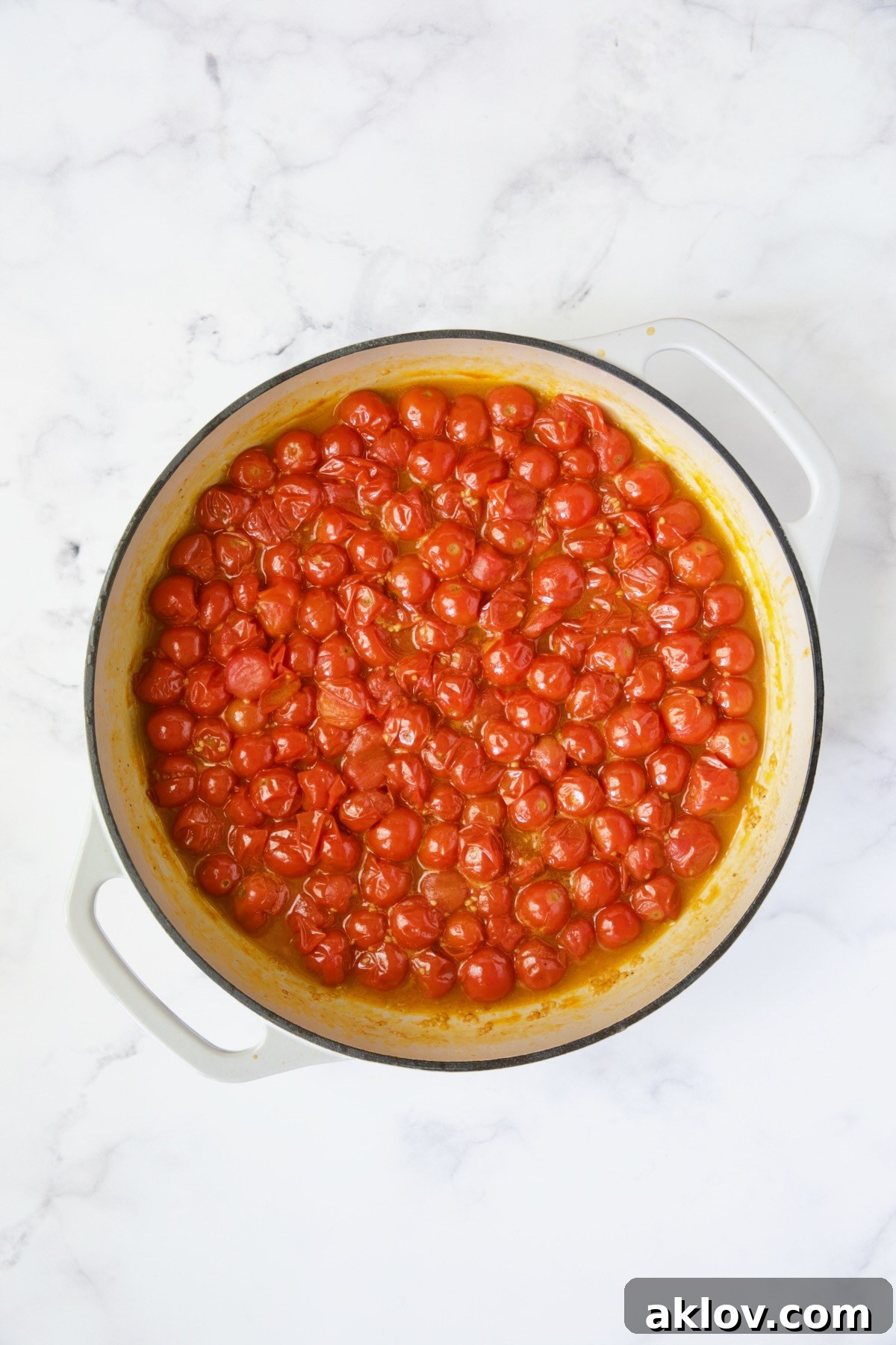 Cooked cherry tomatoes in white enamel cast iron skillet.