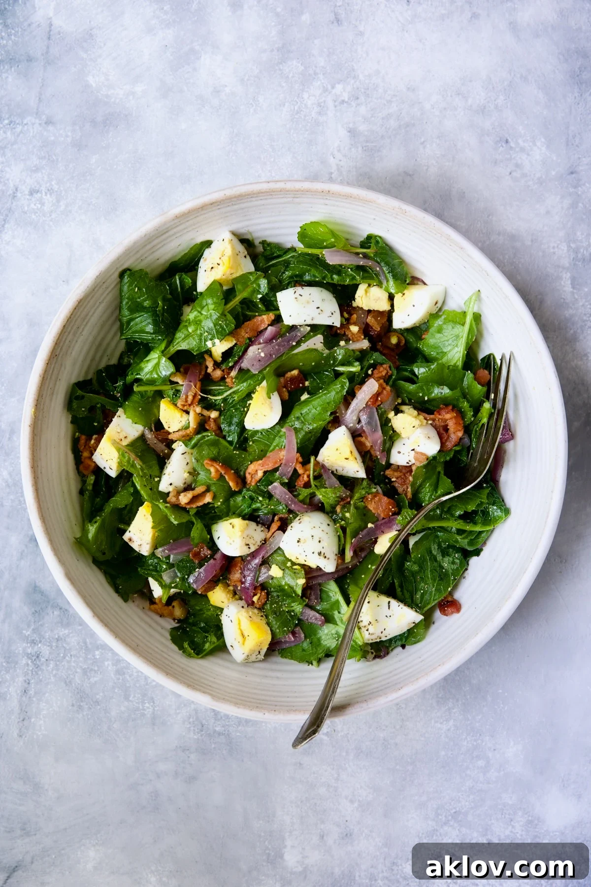 A beautifully presented Radish Greens Salad with Hot Bacon Dressing in a white serving bowl, ready to be enjoyed.