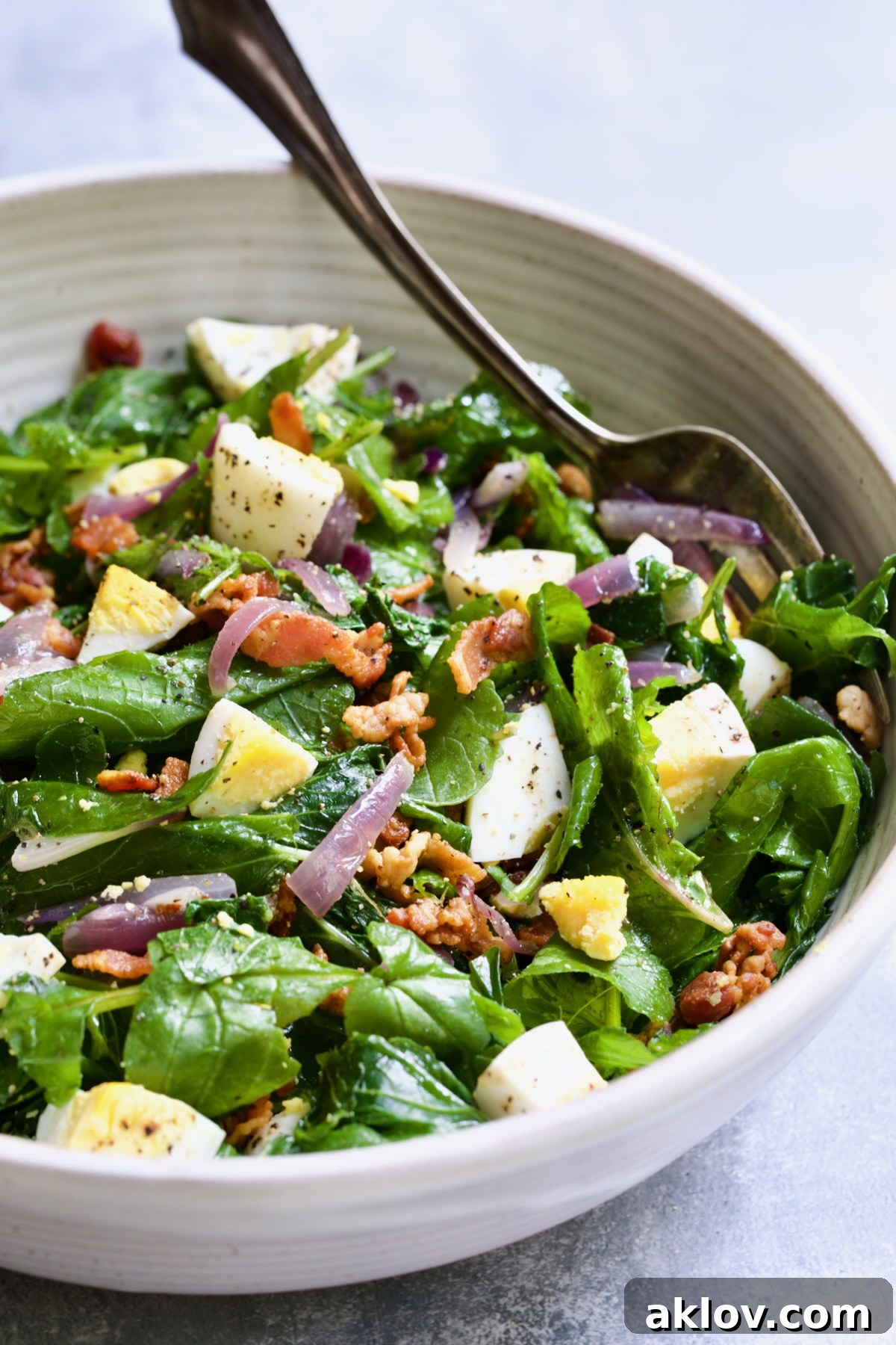 Radish Greens Salad with Hot Bacon Dressing served in a large white bowl, with a fork resting beside it, inviting you to enjoy this fresh and hearty dish.