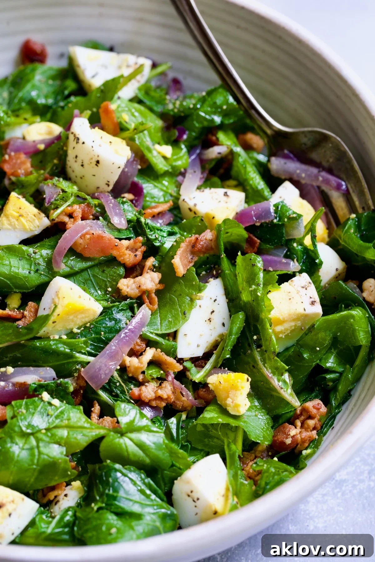 Close-up of Radish Greens Salad with Hot Bacon Dressing in a pristine white serving bowl.