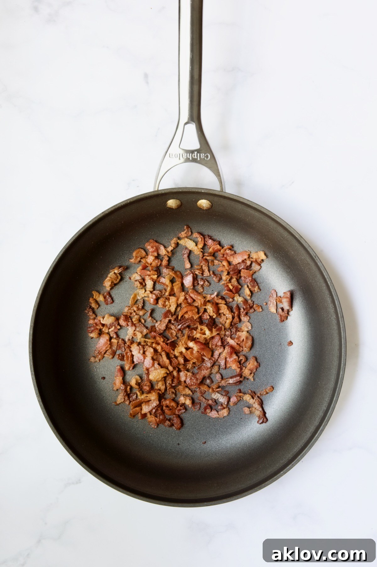 Crispy bacon pieces freshly cooked in a nonstick skillet, ready to be removed for the Radish Greens Salad.