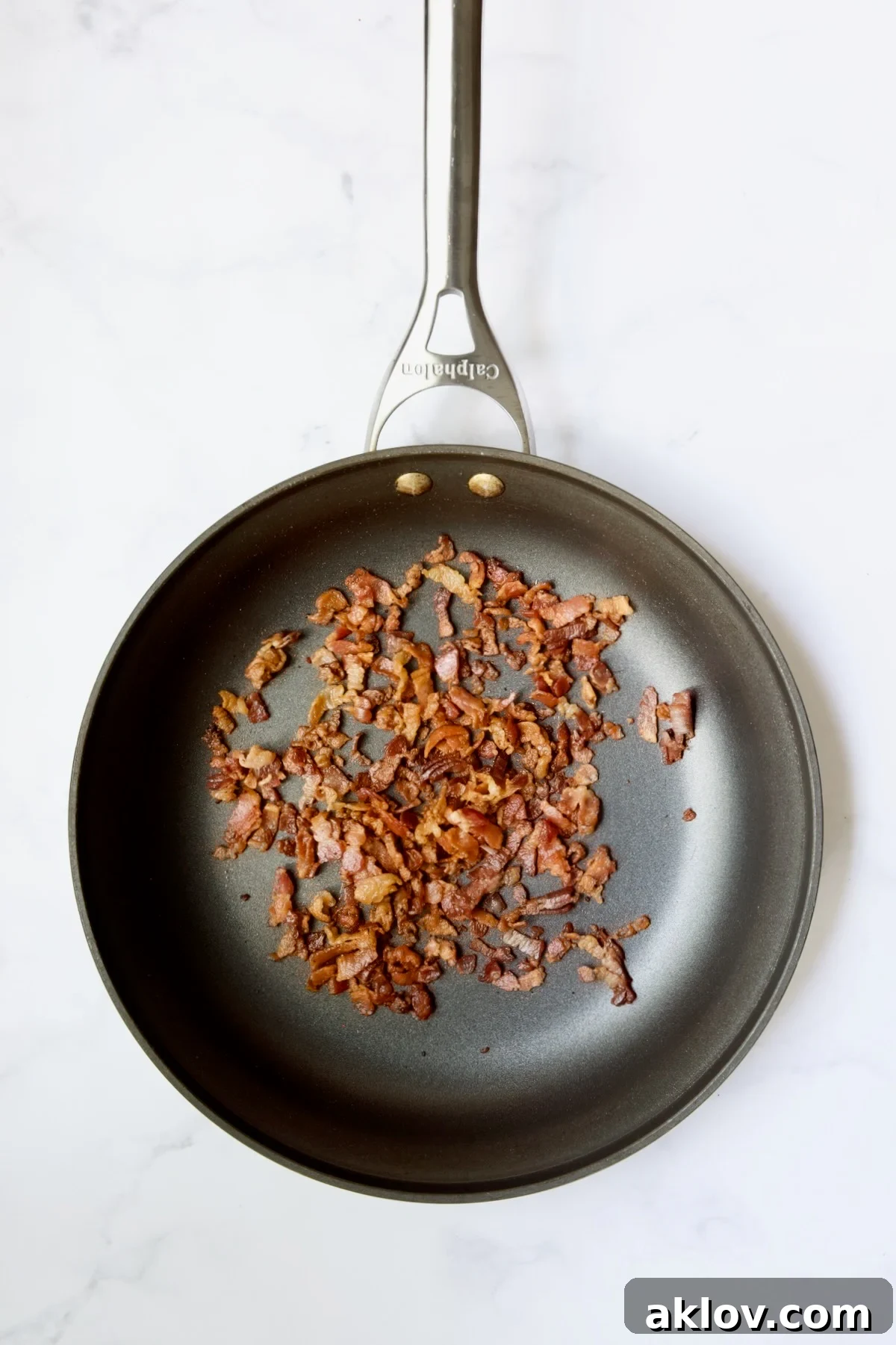 Crispy cooked bacon pieces resting in a nonstick skillet.