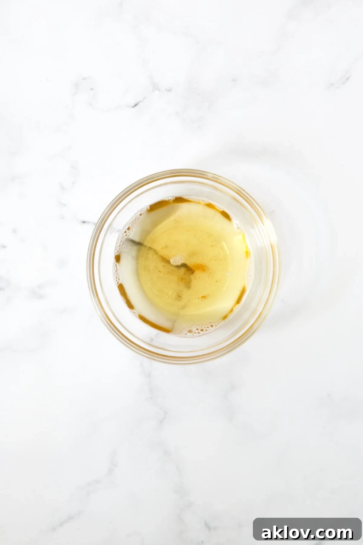 Golden-colored bacon grease collected in a clear glass bowl.