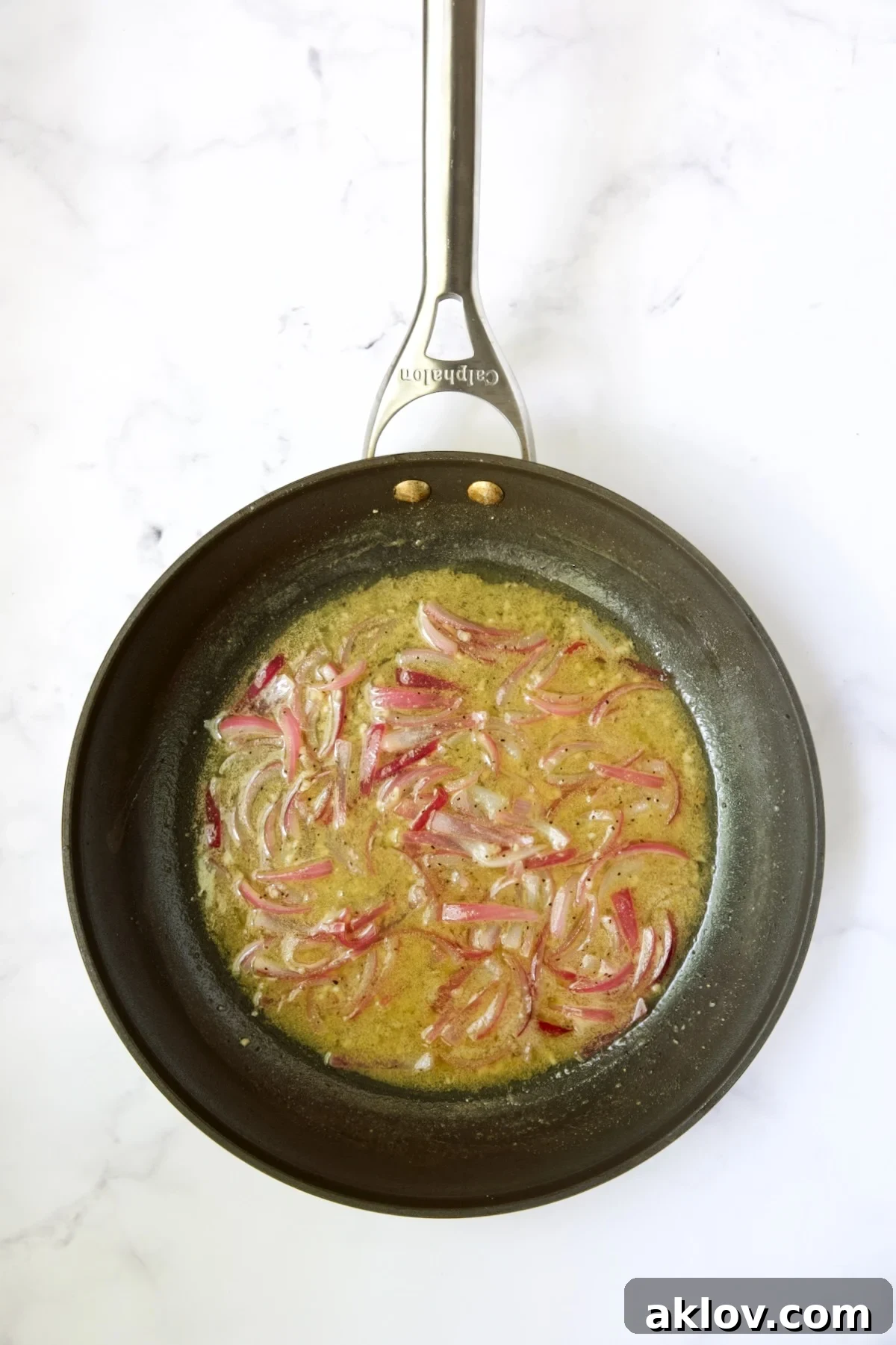 The hot bacon dressing simmering in the skillet with onions.