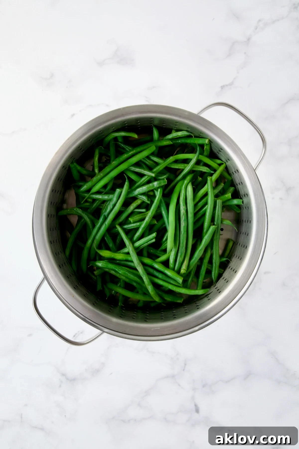 Steamed green beans in steamer rack set over pot.