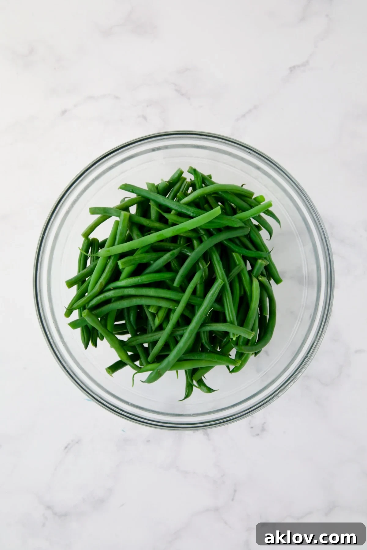 Steamed green beans in glass bowl.