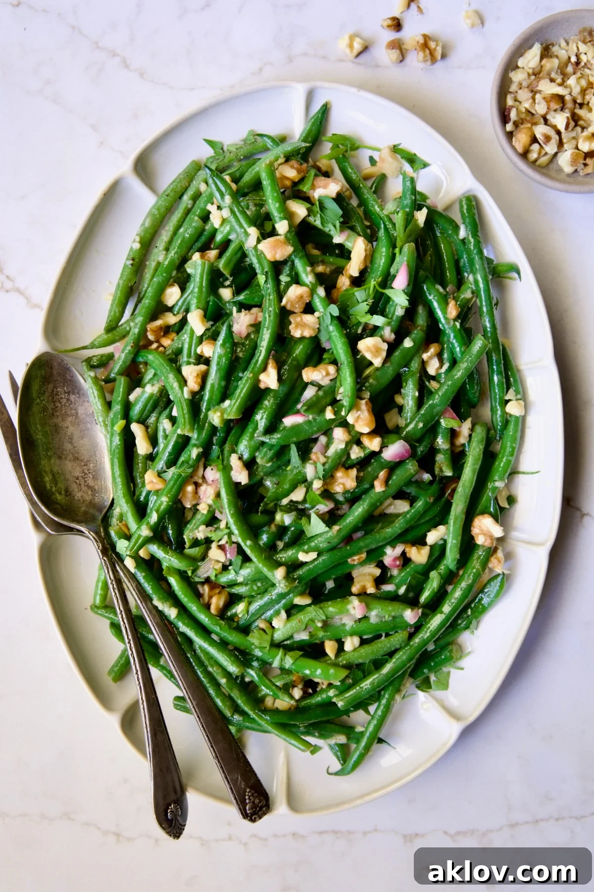 Green Bean Salad with Mustard Vinaigrette on white oval platter garnished with walnuts.